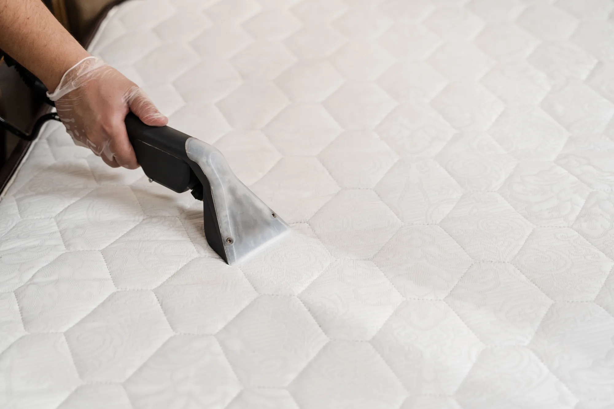 HEPA vacuuming a mattress surface to remove dust mites and allergens